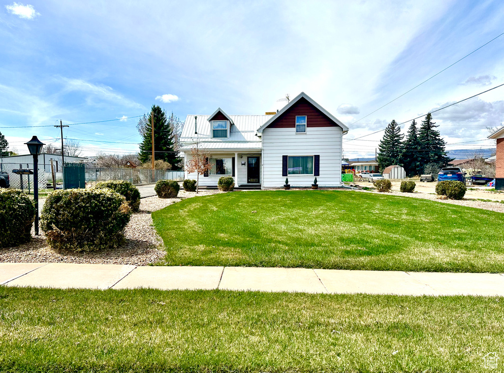 View of front of house with a chimney, metal roof, and a front yard