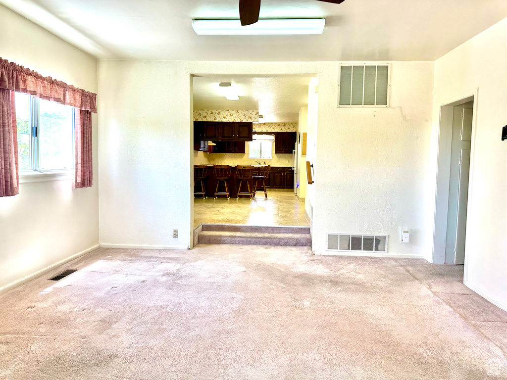 Unfurnished room featuring plenty of natural light, light colored carpet, and ceiling fan
