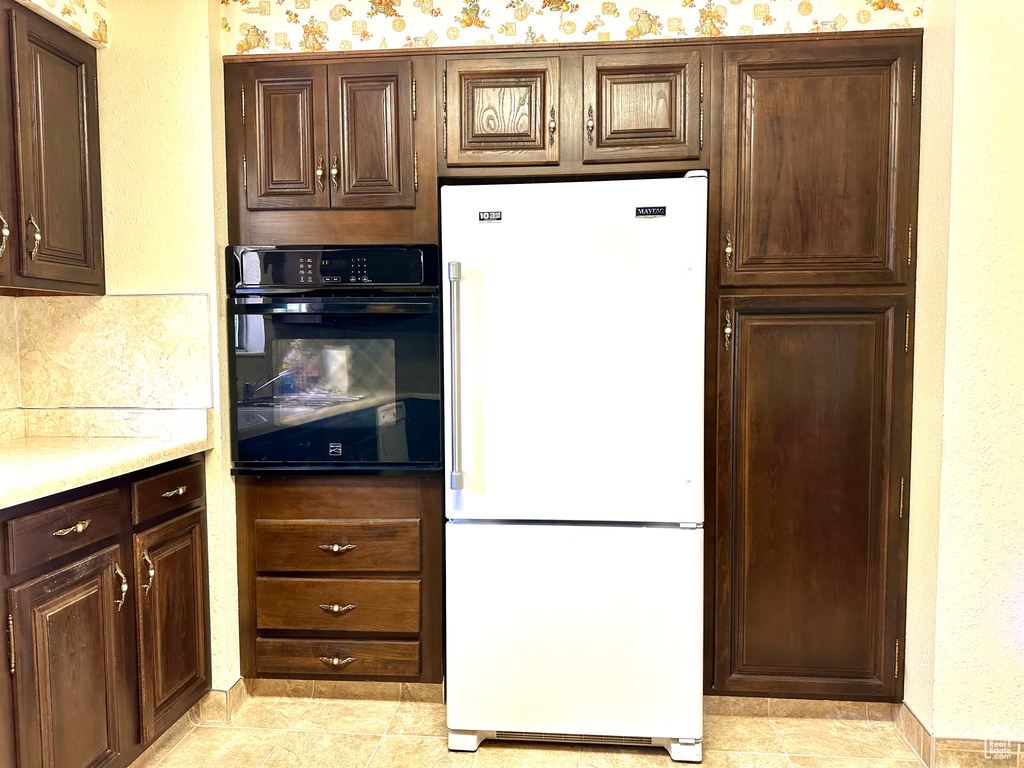 Kitchen featuring high end white fridge, oven, and dark brown cabinets