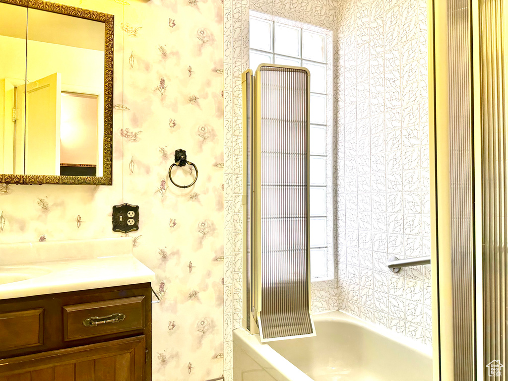 Bathroom with vanity, wallpapered walls, and shower / tub combination