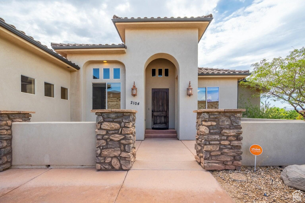 View of exterior entry with a tile roof and stucco siding