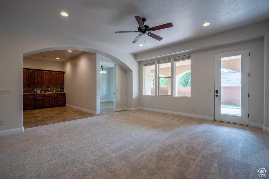 Unfurnished living room with arched walkways, light colored carpet, and recessed lighting