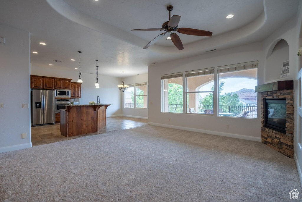 Unfurnished living room with light carpet, baseboards, a fireplace, and a tray ceiling