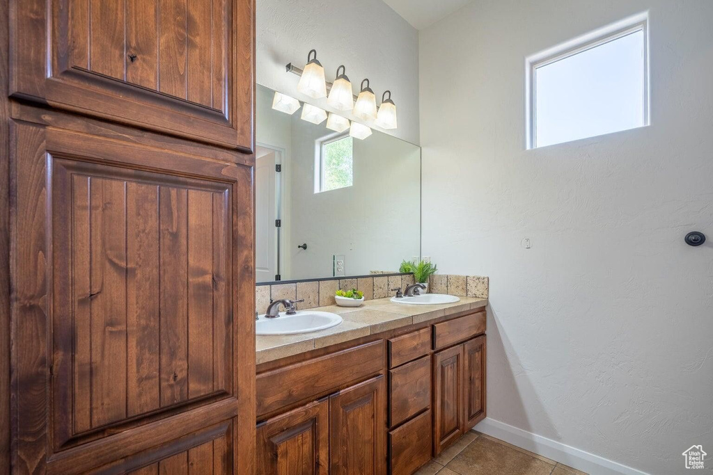 Full bathroom with baseboards, double vanity, a sink, and tile patterned floors