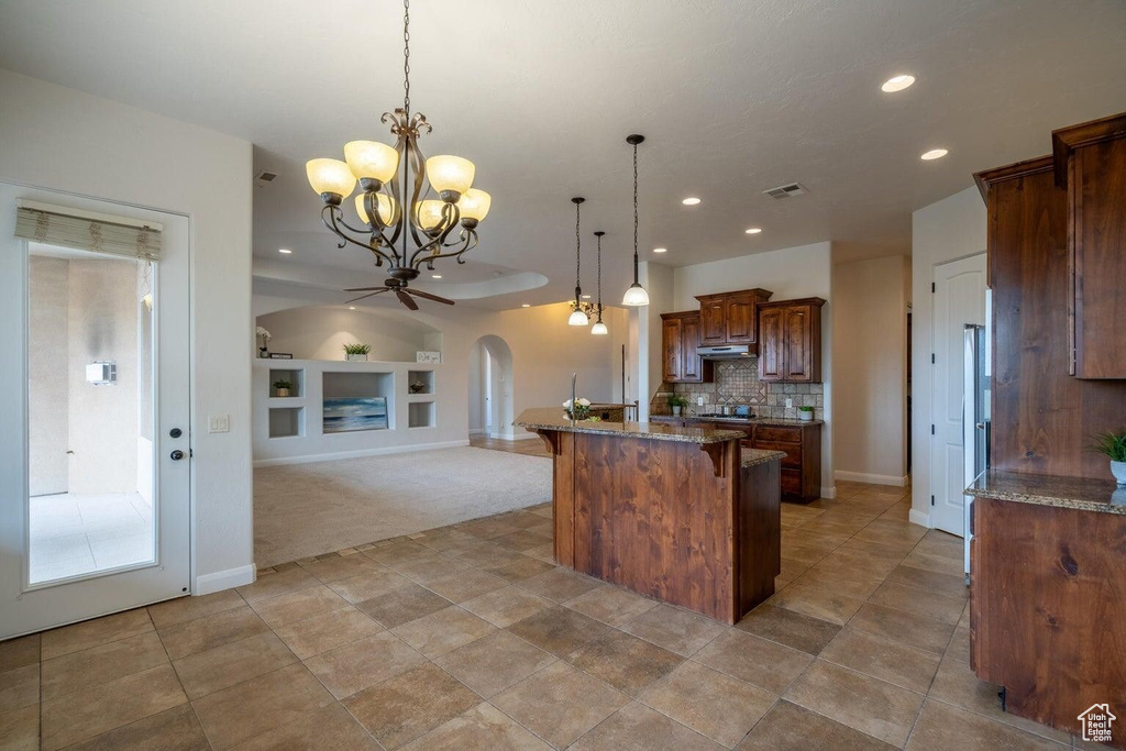 Kitchen featuring visible vents, arched walkways, built in features, a kitchen island, and a kitchen breakfast bar