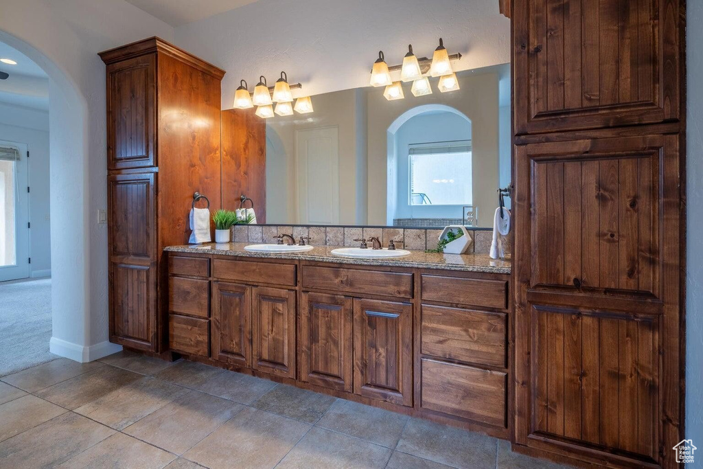 Full bathroom with double vanity, tile patterned flooring, and a sink