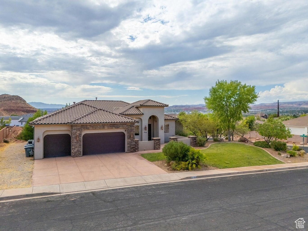 Mediterranean / spanish house featuring an attached garage, a tile roof, concrete driveway, and stucco siding