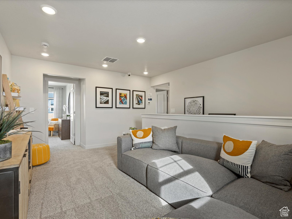 Living room with recessed lighting, visible vents, baseboards, and light colored carpet