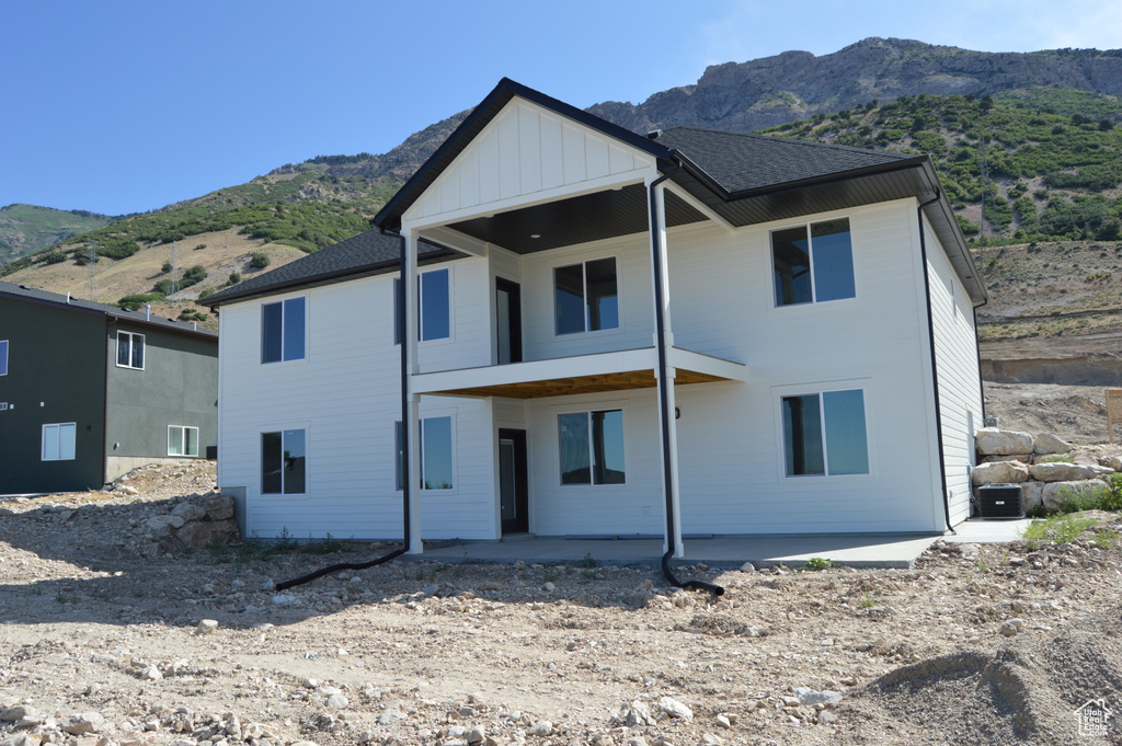 Rear view of house featuring a mountain view, board and batten siding, and a patio