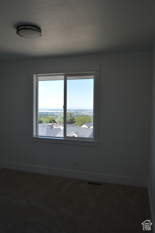 Empty room featuring dark carpet and baseboards