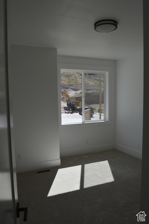 Carpeted spare room featuring baseboards