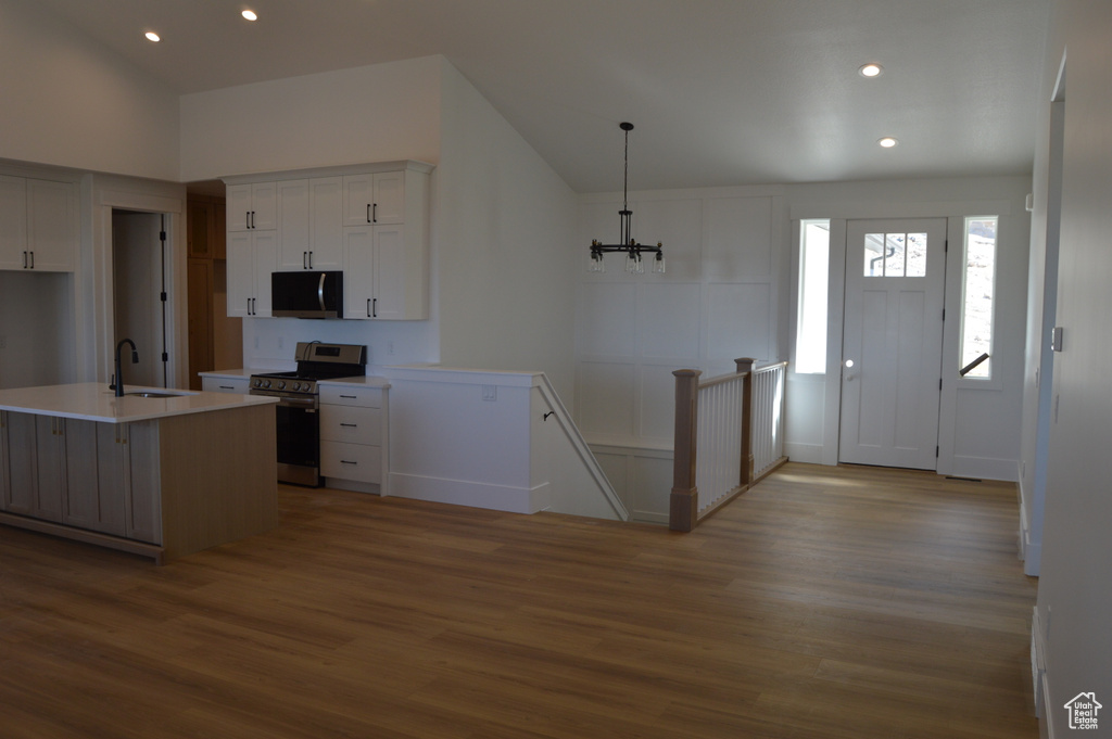 Kitchen featuring stainless steel appliances, wood finished floors, recessed lighting, white cabinetry, and light countertops