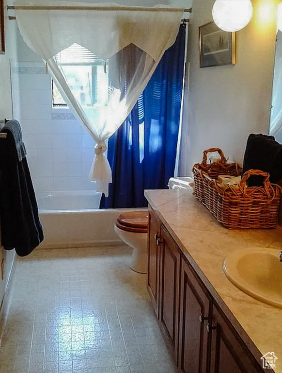 Bathroom with toilet, shower / bath combo with shower curtain, and vanity