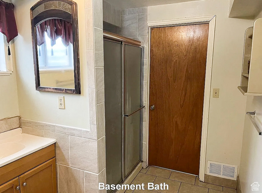 Full bath with tile patterned flooring, vanity, a stall shower, and tile walls