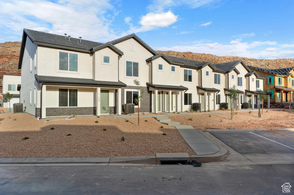 Townhome / multi-family property featuring stucco siding, a residential view, uncovered parking, a mountain view, and brick siding
