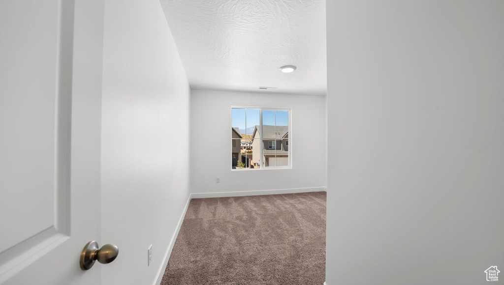 Corridor with baseboards, a textured ceiling, and carpet
