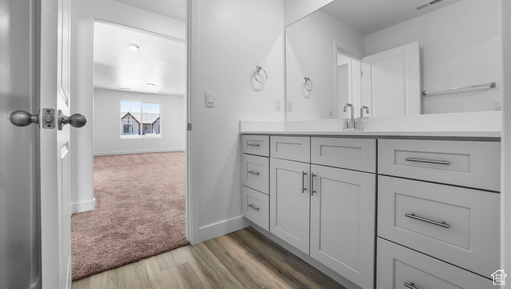 Bathroom with vanity, baseboards, visible vents, and wood finished floors