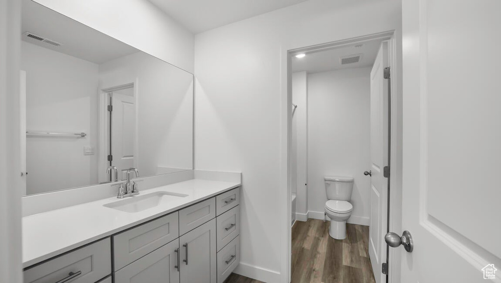 Full bath featuring visible vents, baseboards, toilet, wood finished floors, and vanity