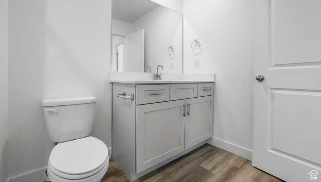 Bathroom featuring toilet, vanity, baseboards, and wood finished floors