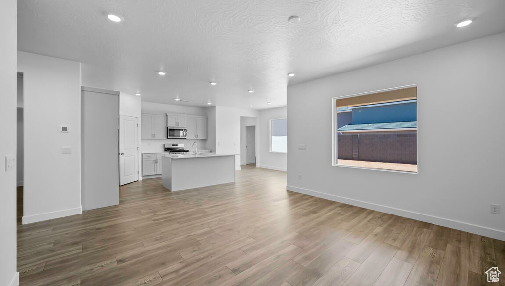 Unfurnished living room featuring baseboards, a textured ceiling, and wood finished floors