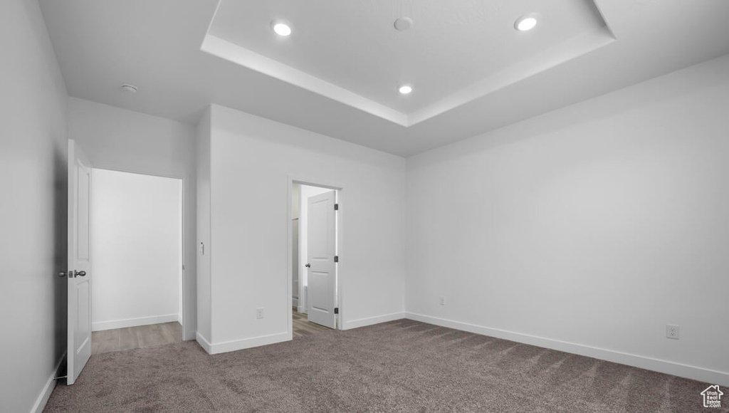 Unfurnished bedroom featuring baseboards, carpet floors, recessed lighting, and a raised ceiling