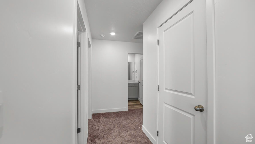 Hall with baseboards, visible vents, and carpet floors