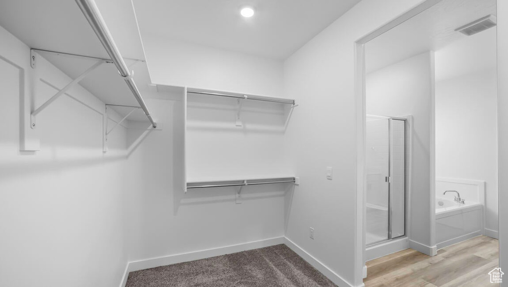 Walk in closet featuring wood finished floors and visible vents
