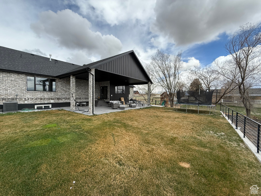 View of yard with a trampoline, cooling unit, fence, outdoor lounge area, and a patio