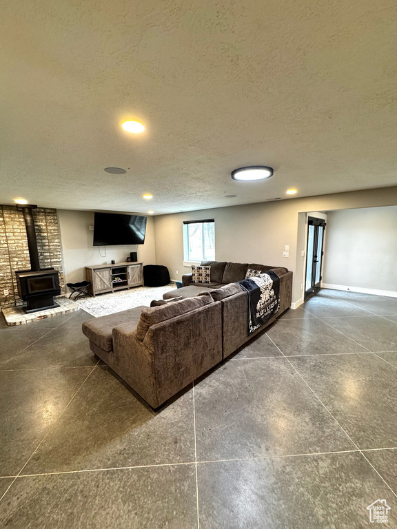 Living room featuring a wood stove, a textured ceiling, recessed lighting, and baseboards