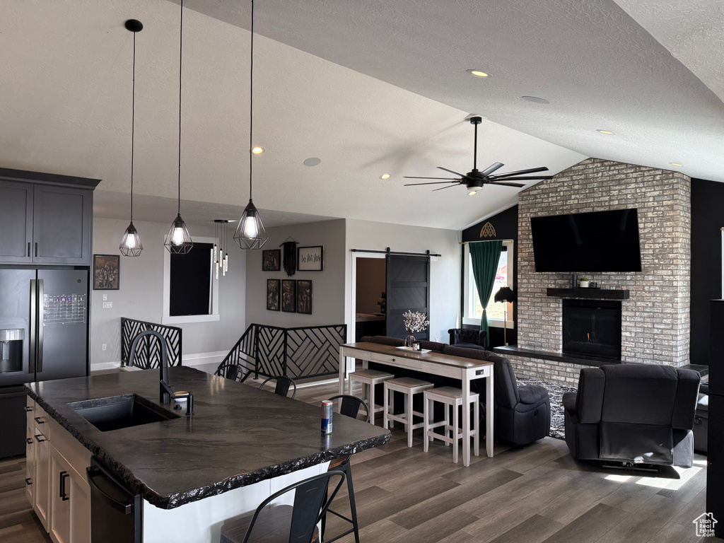 Kitchen with refrigerator with ice dispenser, a sink, a barn door, open floor plan, and ceiling fan
