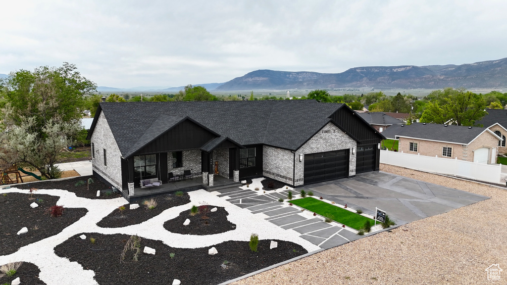 View of front of property featuring an attached garage, a porch, a mountain view, board and batten siding, and asphalt driveway