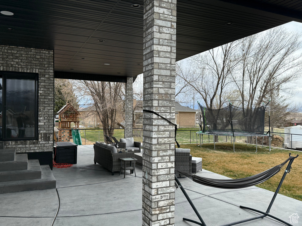 View of patio with a trampoline, a playground, an outdoor hangout area, and fence