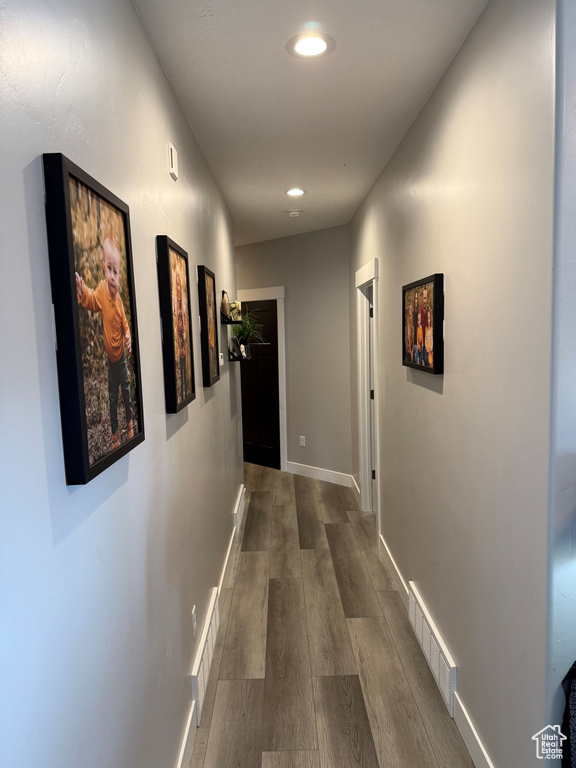 Hall featuring dark wood-type flooring, baseboards, visible vents, and recessed lighting