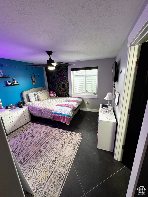 Bedroom with a textured ceiling, a ceiling fan, and baseboards