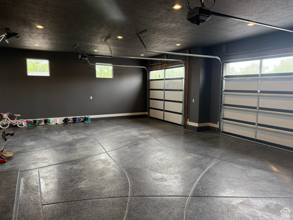 Garage with a garage door opener, baseboards, and recessed lighting