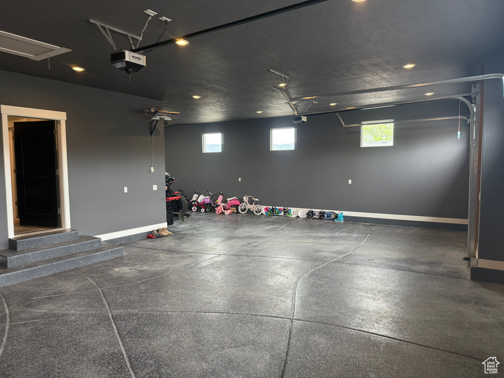Garage with recessed lighting, a garage door opener, and baseboards