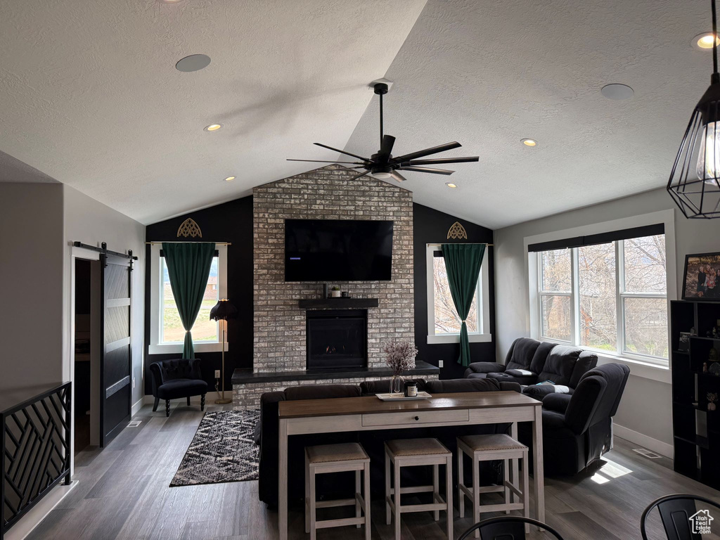 Living area with lofted ceiling, a fireplace, wood finished floors, and a ceiling fan