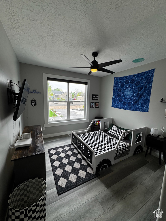 Bedroom featuring wood finished floors, a textured ceiling, ceiling fan, and baseboards
