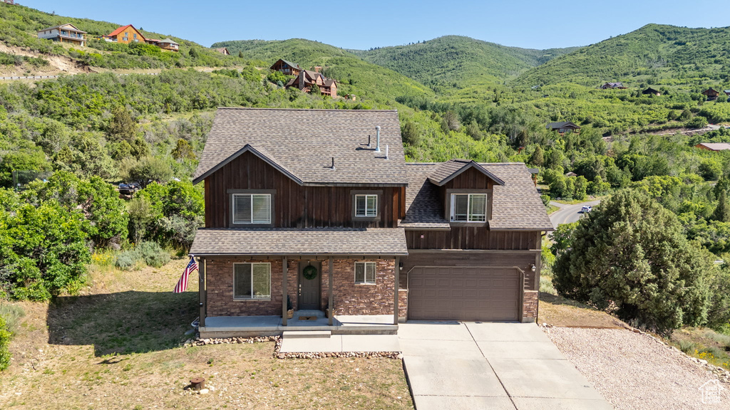 View of front of property featuring a porch, an attached garage, concrete driveway, and a mountain view