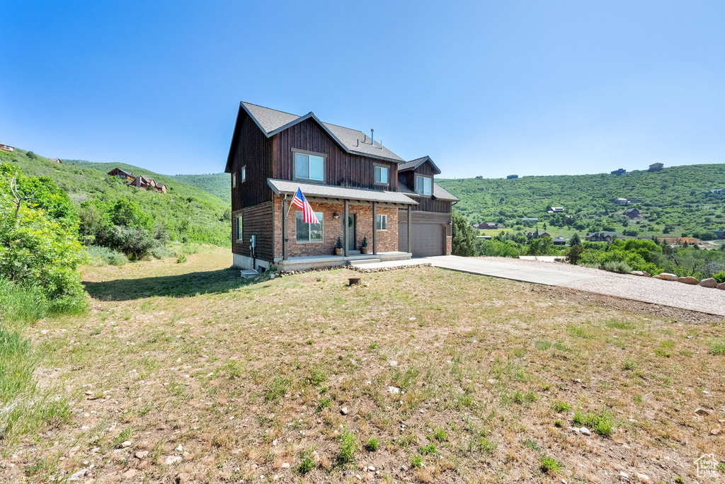 View of front of home featuring driveway, brick siding, a front yard, and board and batten siding