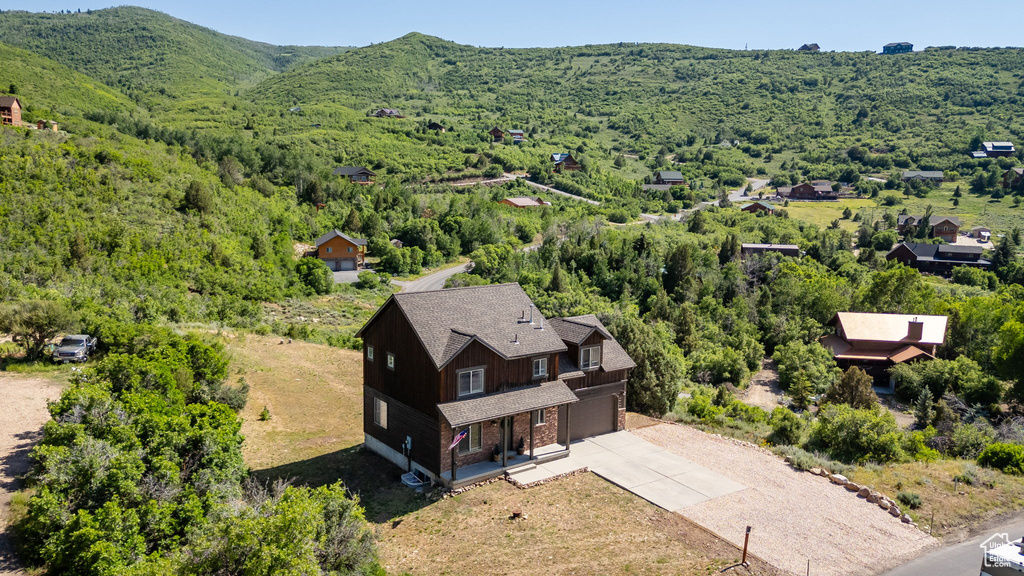 Aerial view of property and surrounding area with a forest and a mountainous background