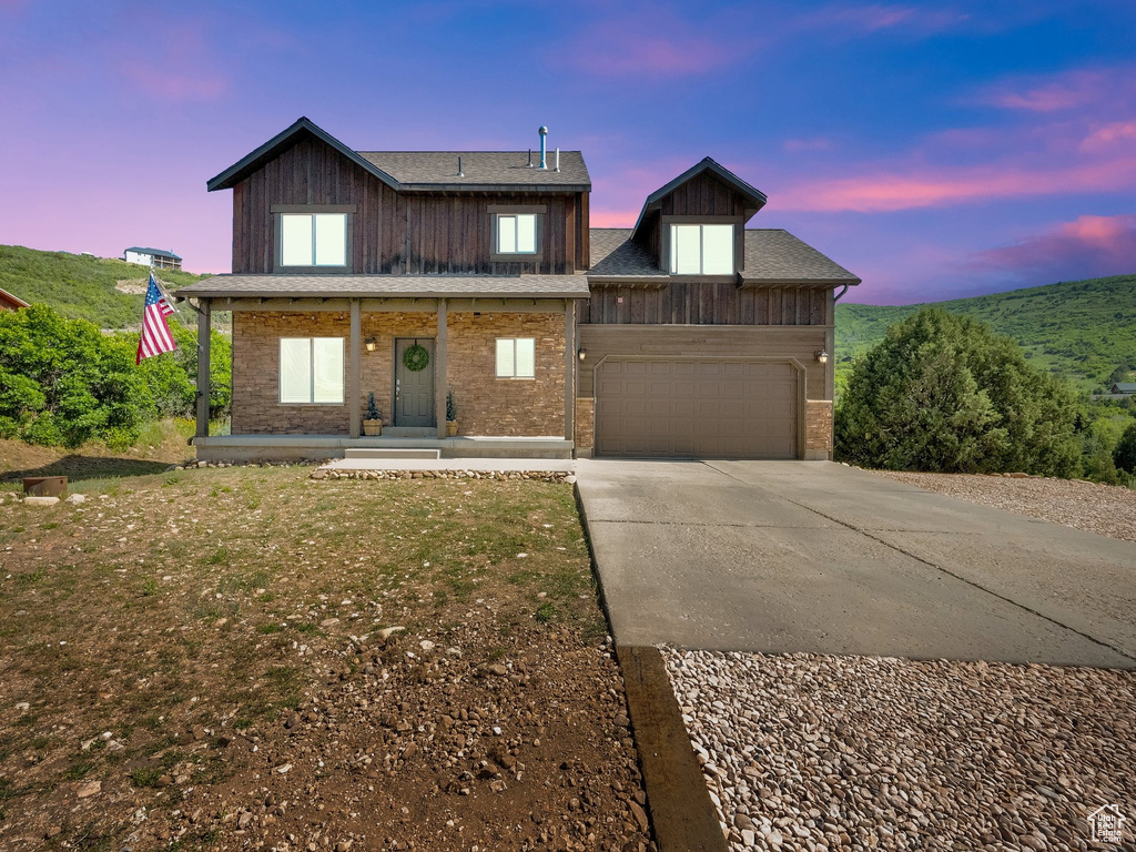 View of front of house featuring concrete driveway, a garage, and a porch
