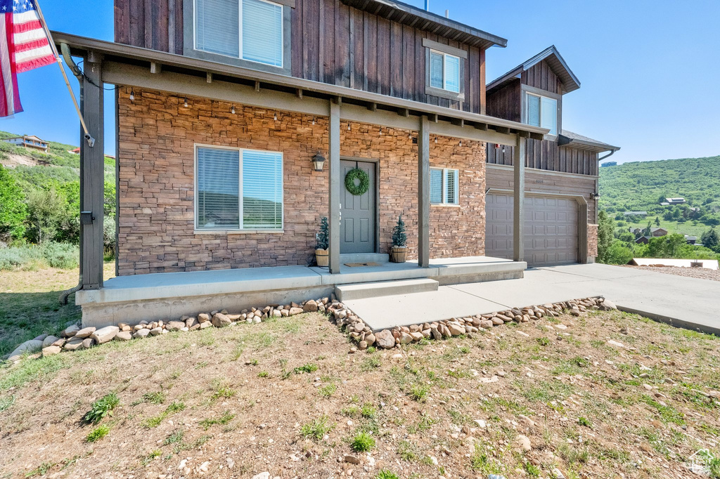 View of front of house with driveway, board and batten siding, stone siding, and an attached garage