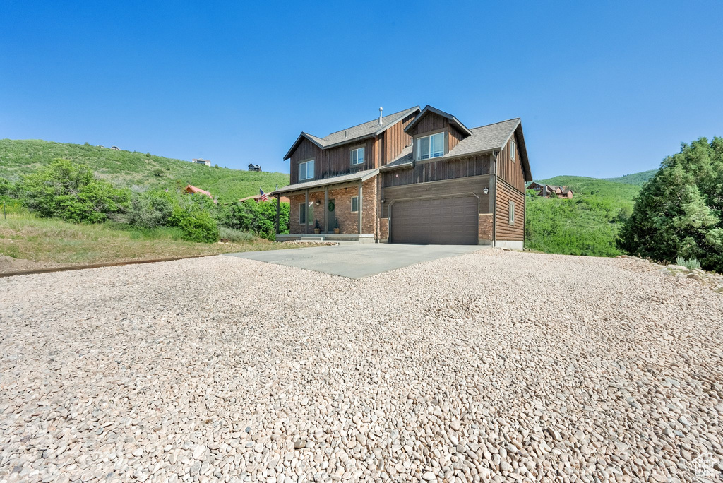 View of front of home with driveway, solar panels, brick siding, and an attached garage