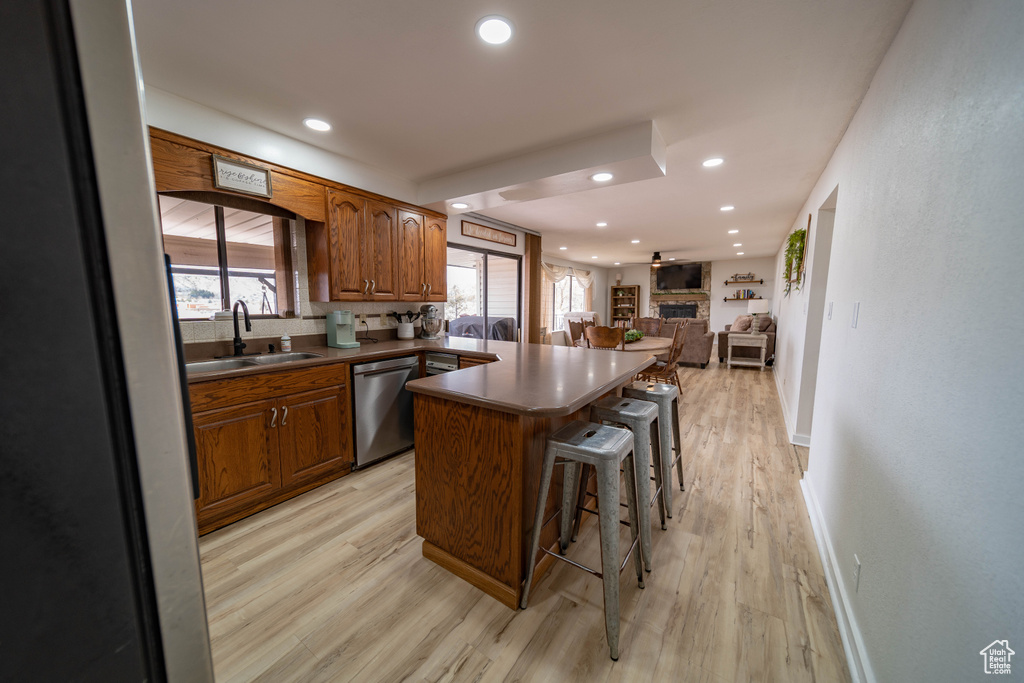Kitchen featuring open floor plan, a breakfast bar, a sink, light wood finished floors, and appliances with stainless steel finishes