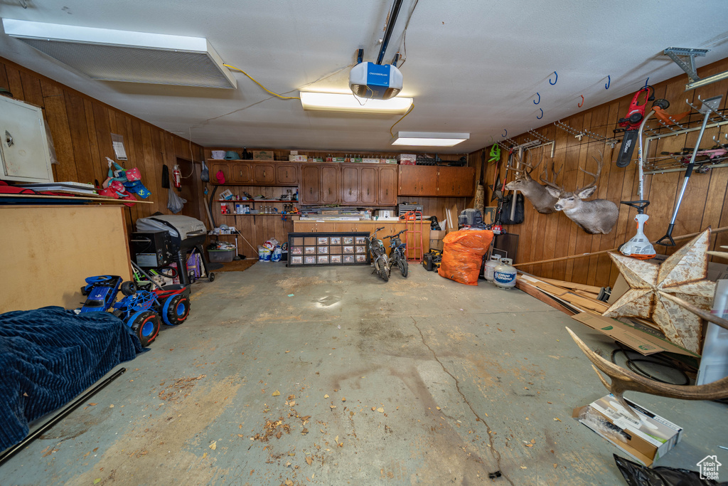 Garage featuring a workshop area, wood walls, and a garage door opener