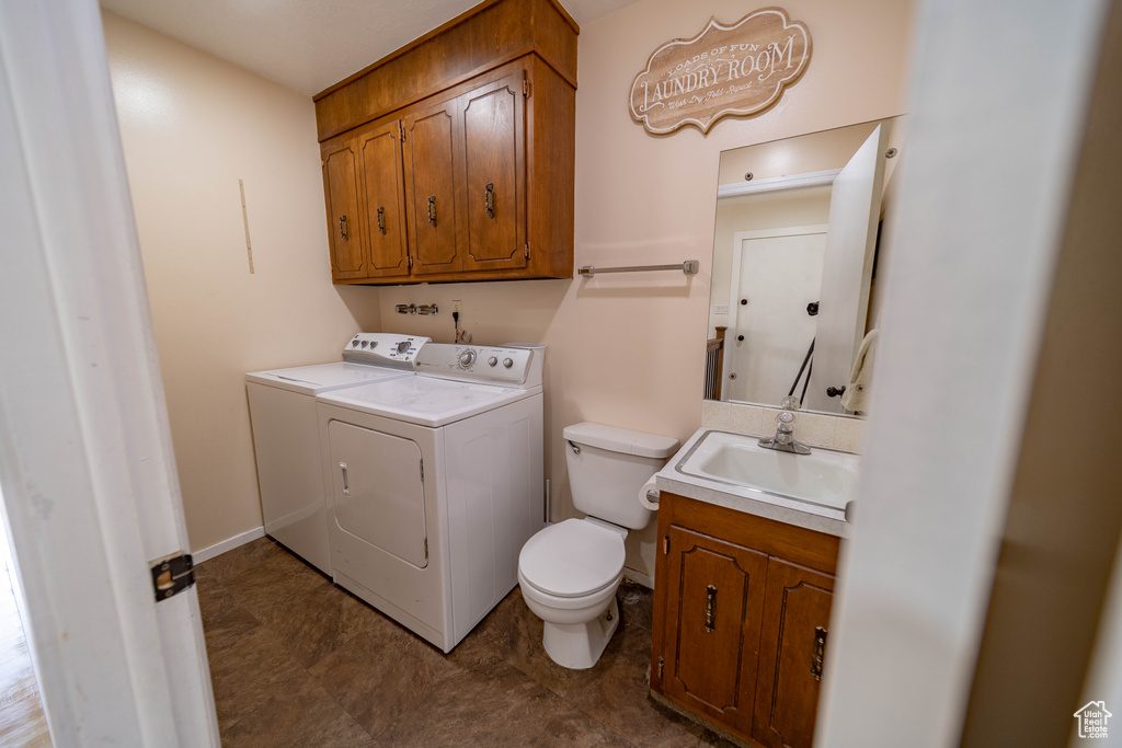 Clothes washing area with baseboards, separate washer and dryer, laundry area, and a sink