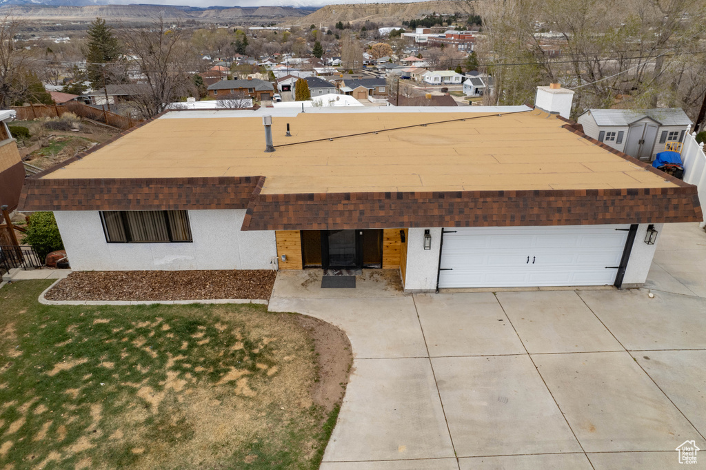 View of front facade with stucco siding, an attached garage, driveway, a front yard, and a mountain view