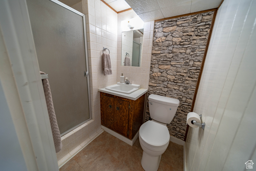 Bathroom with toilet, vanity, a stall shower, and tile patterned flooring