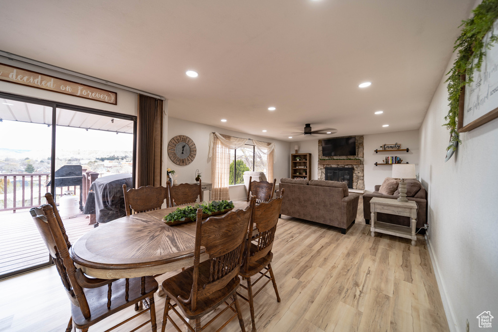 Dining space with a stone fireplace, light wood-type flooring, recessed lighting, and a ceiling fan